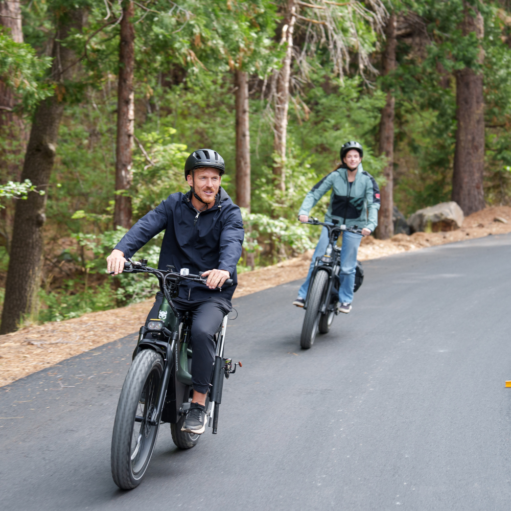 Two riders cruising Cycrown Nomad Pro e-bikes along a quiet forest road.