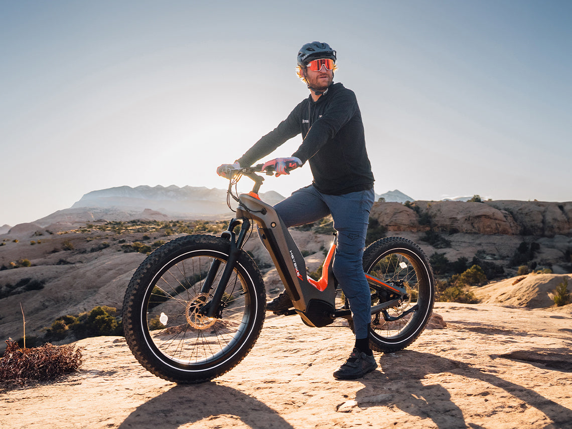 Heybike Hero carbon-fiber full-suspension fat-tire electric mountain bike with two motor configurations (1000W rear hub or 750W mid-drive with torque sensor), step-thru or step-over frame geometry, Shimano 9-speed gearing, hydraulic disc brakes, and UL 2849 certified electrical system