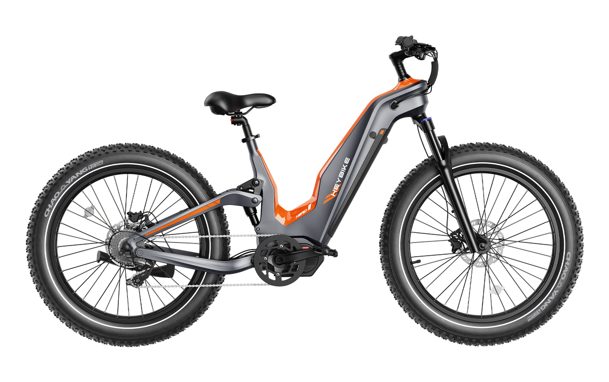 Tangerine and gray Heybike Hero carbon-fiber full-suspension electric mountain bike with the step-thru frame option, 26 by 4 inch fat tires, mid-drive motor at the bottom bracket, brown saddle, hydraulic disc brakes, and Shimano 9-speed rear derailleur, shown in studio side profile