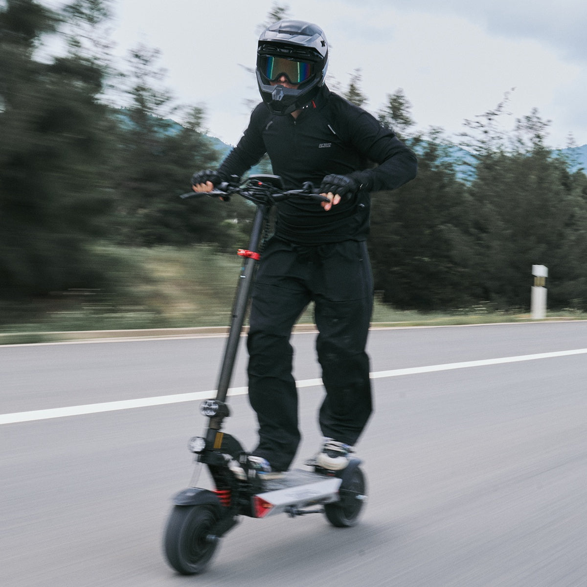 Helmeted rider on the Circooter Landturbo Ultra riding on a paved open road with full-face helmet and gloves.