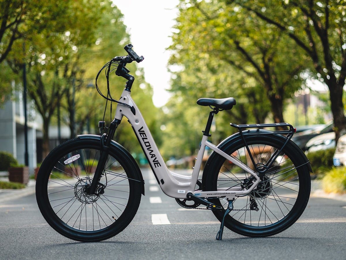 Beige Velowave Breeze T parked on a city street with step-through frame and rear rack
