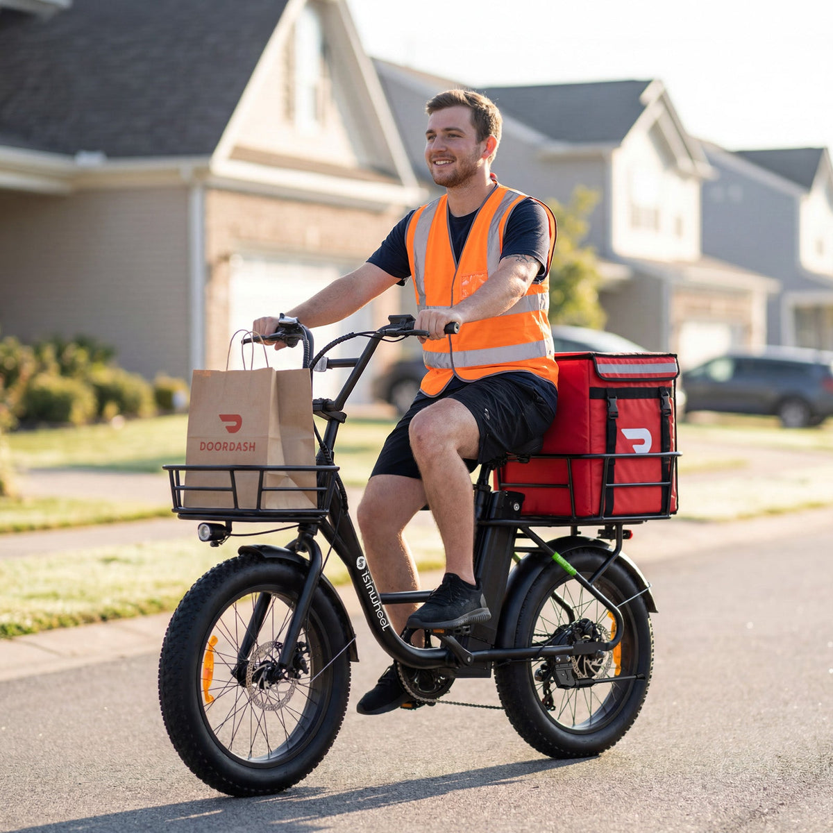 Gig delivery rider in an orange safety vest riding the isinwheel U7 in a suburban street with a DoorDash bag in the front basket and a large red DoorDash insulated bag on the rear rack