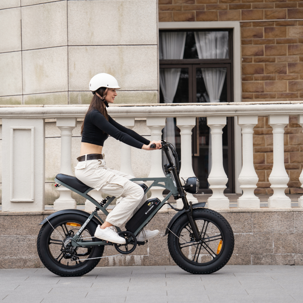 Helmeted rider passing a city building on the mint green bike