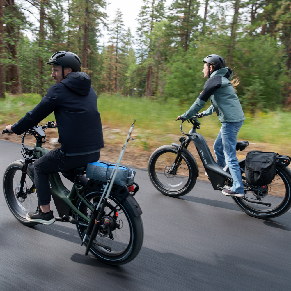 Two Nomad Pro riders traveling along a wooded road with rear racks and fat tires visible.