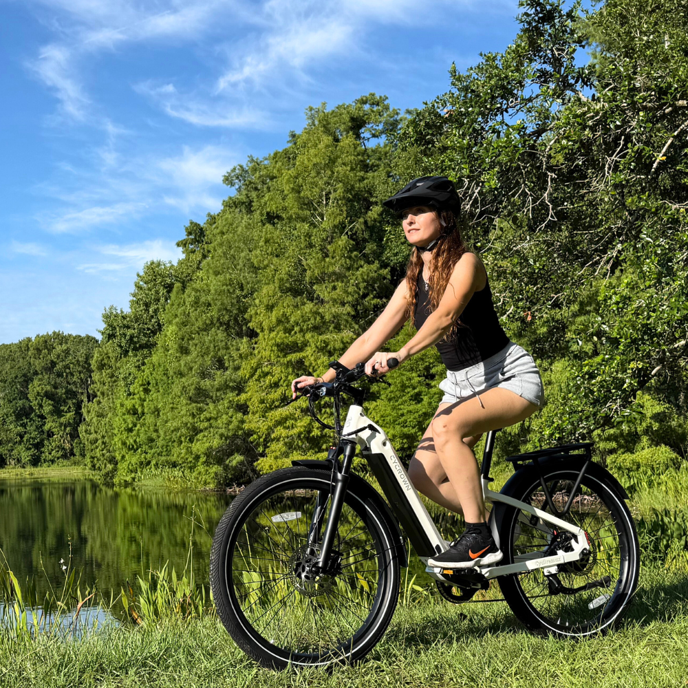 Rider using the white Dremax beside a wooded pond on a calm recreational route.