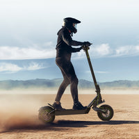 Helmeted rider using the S10Max on a dry open path with hills in the distance