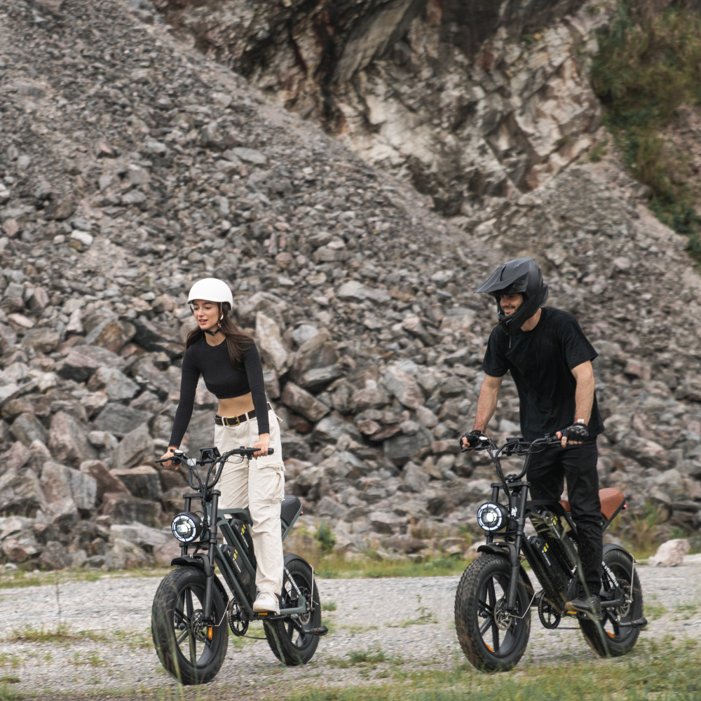 Two riders walking CycHunter e-bikes across loose rocky ground