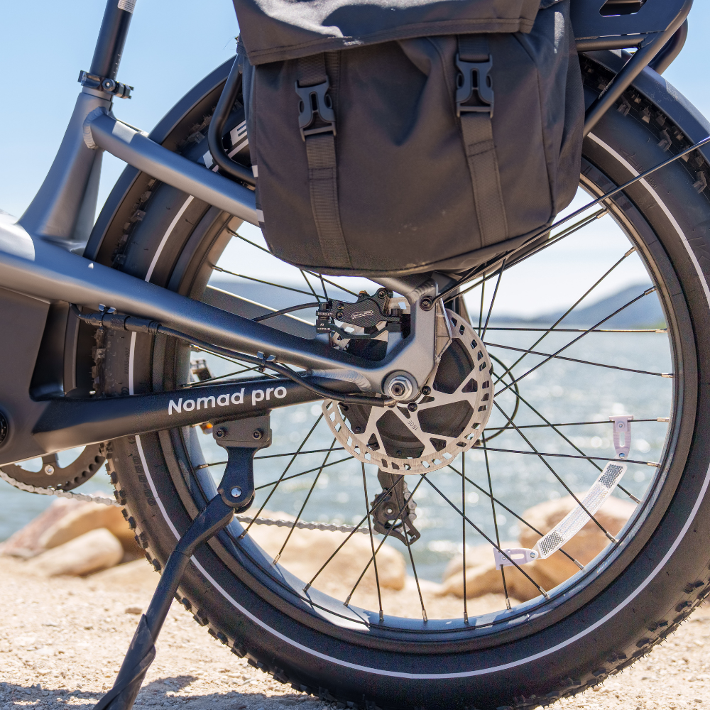 Rear wheel, kickstand, drivetrain guard, and loaded rack on a graphite grey Nomad Pro.