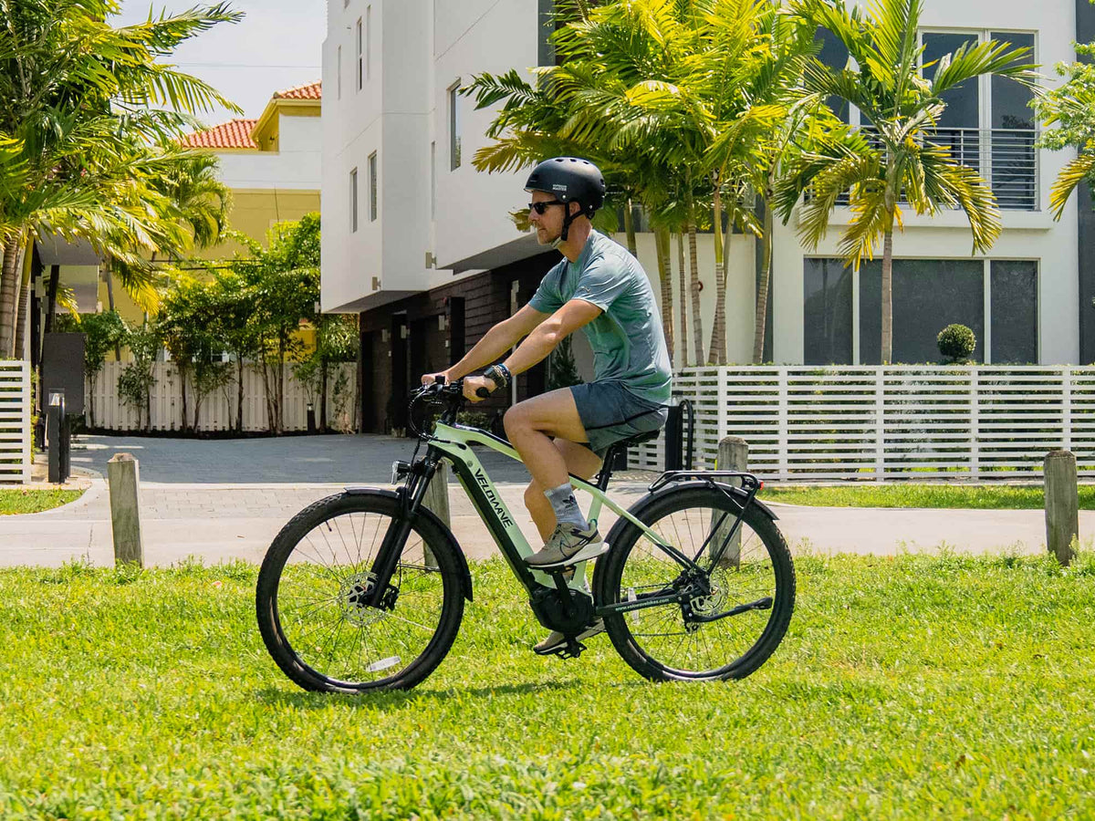Helmeted rider pedaling a Macaron Green Swift M on a neighborhood path