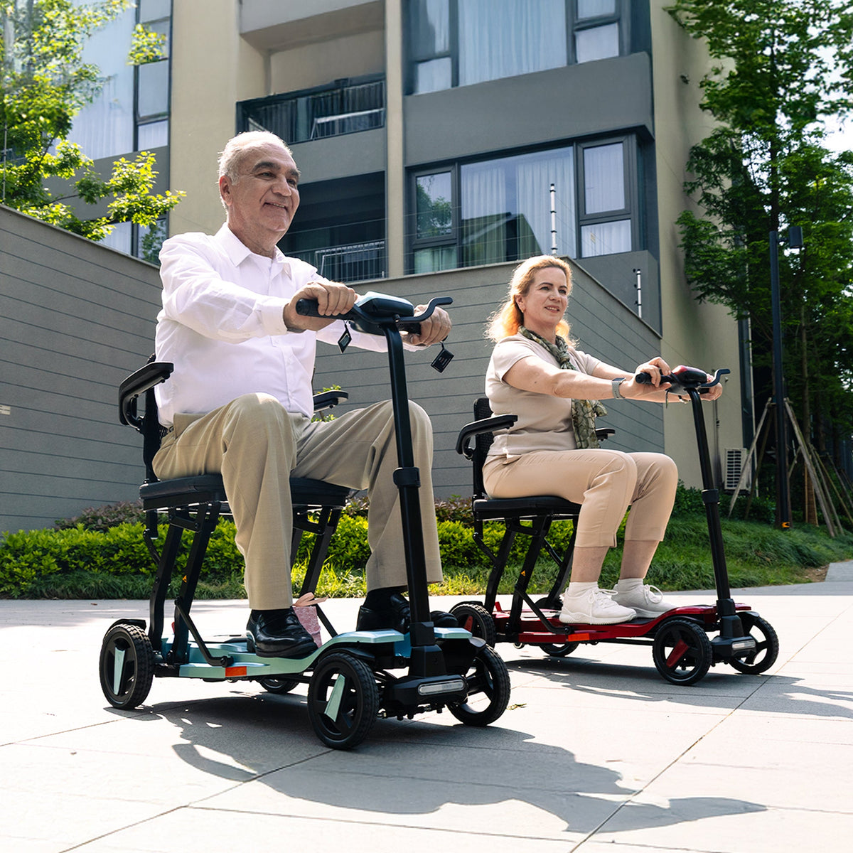 Two adults riding ScootNGo Voyager mobility scooters on a paved path