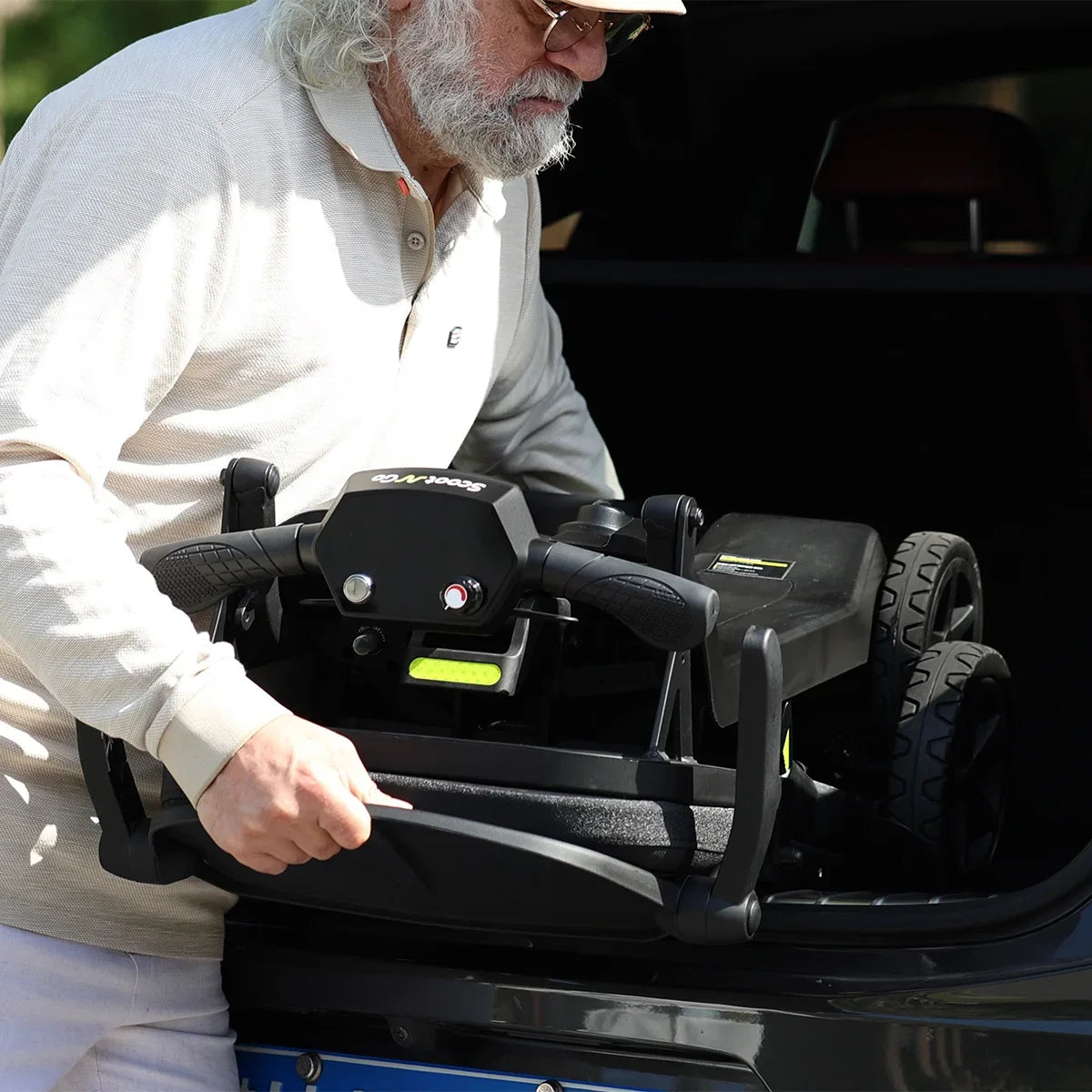 Adult lifting a folded ScootNGo Lite mobility scooter into a vehicle trunk