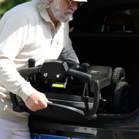 Adult lifting a folded ScootNGo Lite mobility scooter into a vehicle trunk