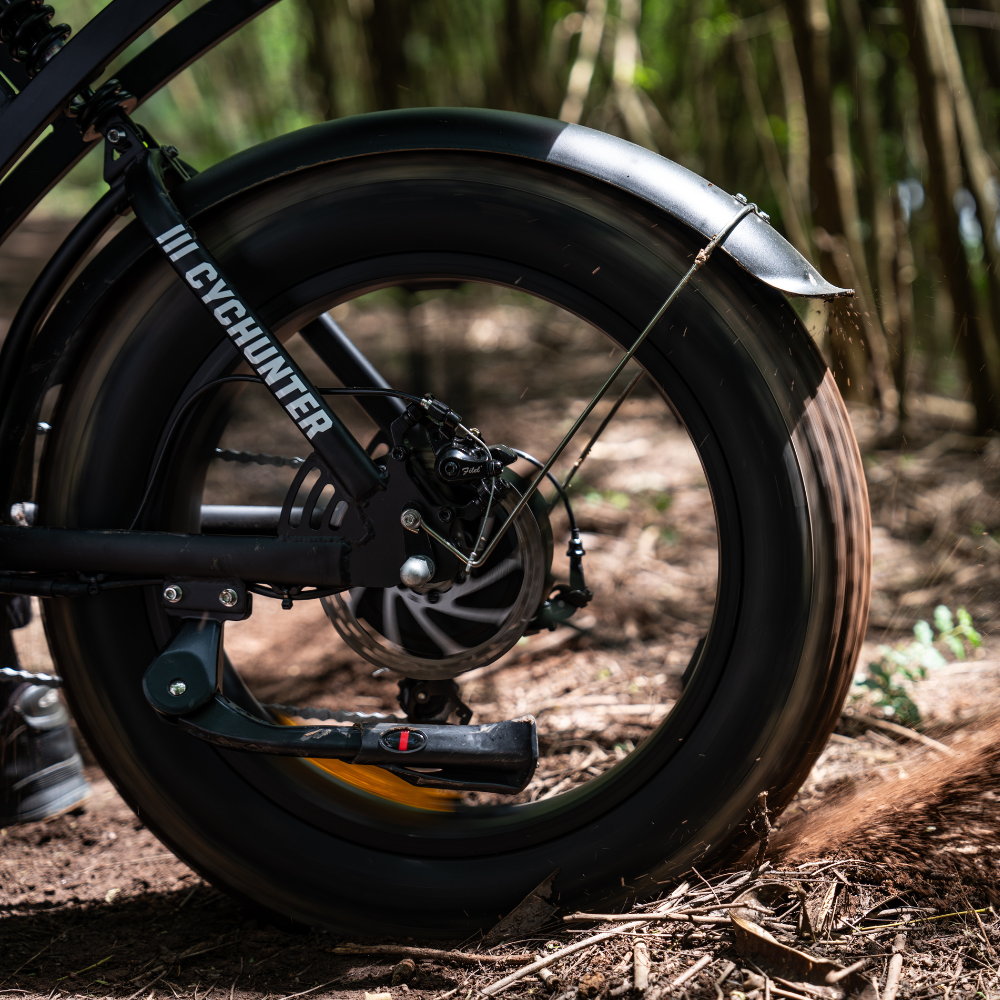 Rear fat tire, motor housing, disc brake, and fender in the woods