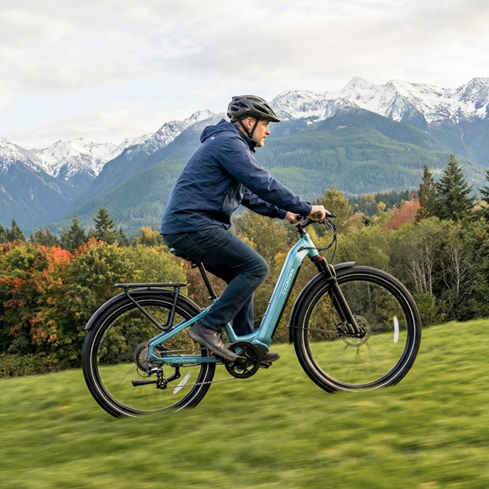 Helmeted rider using the teal Dremax on a mountain road with the upright commuter fit visible.