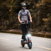 Side profile of the iScooter iX8 with a rider standing on the deck on a paved private road, showing the upright handlebar stance