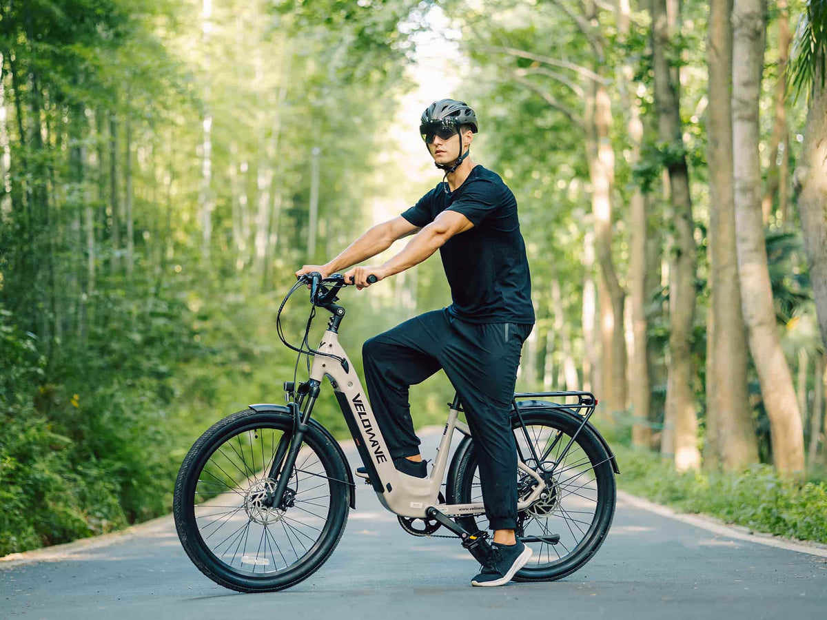 Helmeted rider using a Beige Velowave Breeze T on a tree-lined paved path