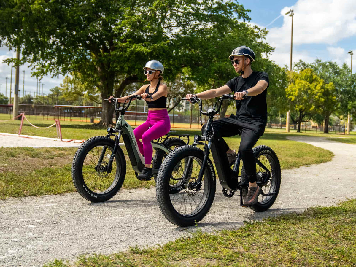 Two riders on Velowave step-through electric bikes on a paved park path