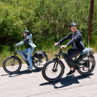 Grey and green Nomad Pro e-bikes riding together, showing both color choices in use.