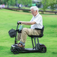 Adult riding a ScootNGo Folo mobility scooter on grass with a front bag