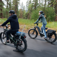Two Nomad Pro riders rounding a bend beneath tall pine trees