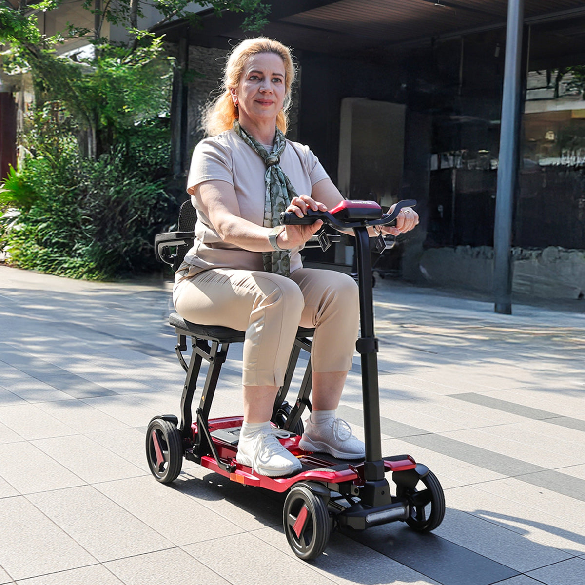 Adult riding a Wine Red ScootNGo Voyager near a building entrance