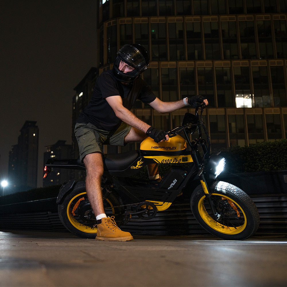Front three-quarter studio view of the yellow HappyRun G100 Pro Tank with the matte black frame and yellow accents on the rims, headlight bracket, and tank graphics