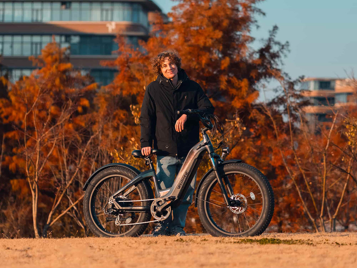 Rider standing with a Velowave Grace 2.0 Step-Thru electric bike in autumn