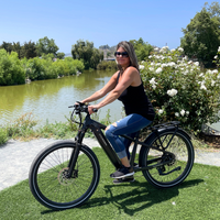 Woman riding the black Dremax beside a lake on a paved recreational path.