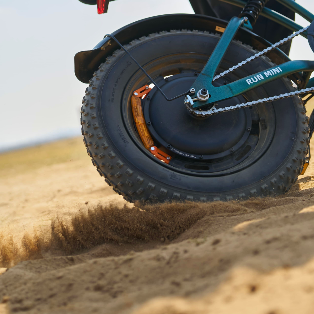 Rear fat tire throwing dust on the alpine green Run Mini