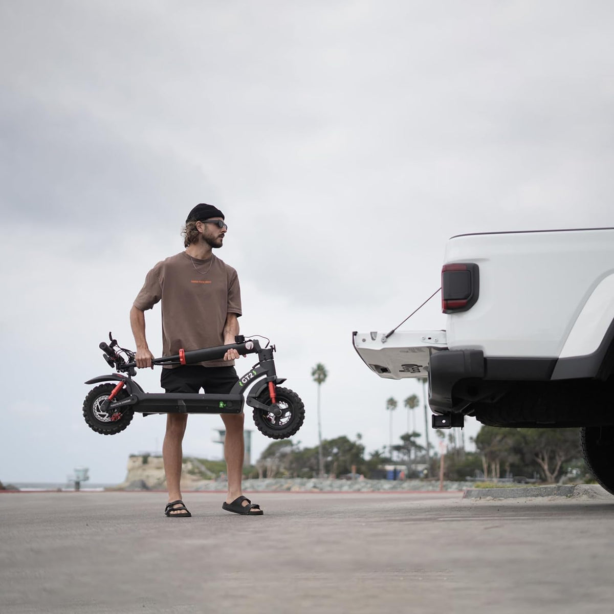 Man carrying the folded GT2 beside an SUV to show its transport size