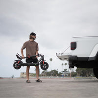Man carrying the folded GT2 beside an SUV to show its transport size