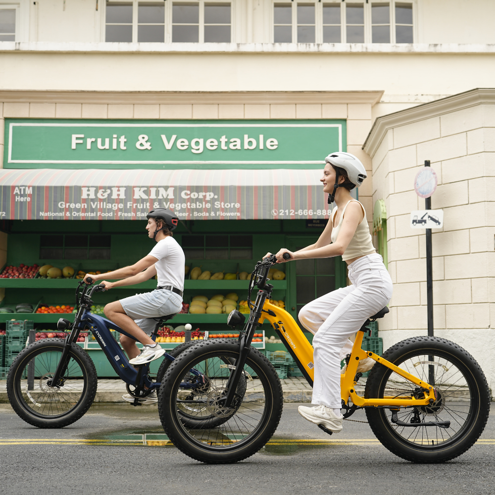 Riders passing a neighborhood market on blue and yellow Roma e-bikes
