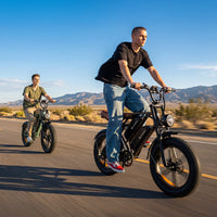 Two riders cruising on CycHunter e-bikes along a sunny mountain road
