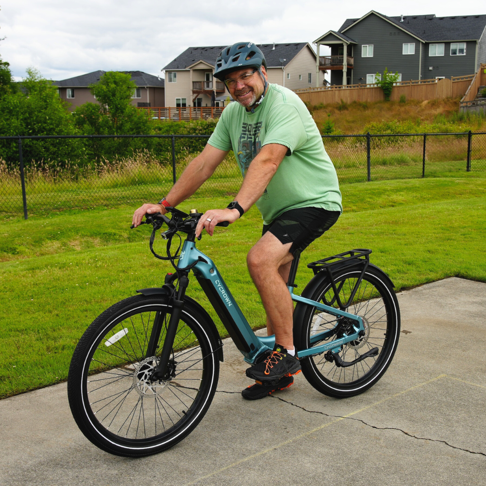 Helmeted rider smiling while using the teal step-through Dremax on a casual road ride.