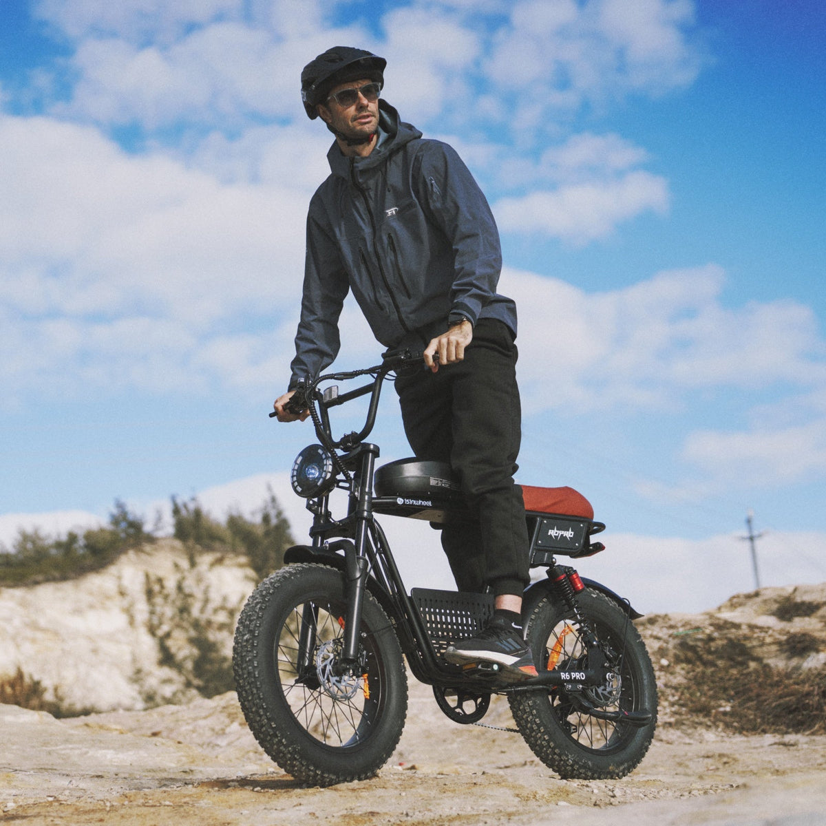 Side profile of the isinwheel R6 Pro showing the moped-shaped tank cover with R6 Pro graphics, the rear coil-over shock, and the kickstand on a plain studio background