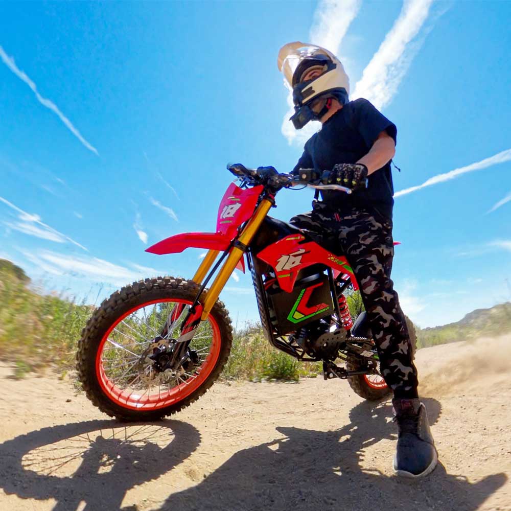 HappyRun F18 motocross-shaped electric dirt bike with a 6000W peak mid-drive motor, 245 Nm of peak torque through a chain drive, knobby off-road tires, full suspension, hydraulic disc brakes with a 190mm rotor, IPX5 water resistance, and a motocross frame in red and black with number plates