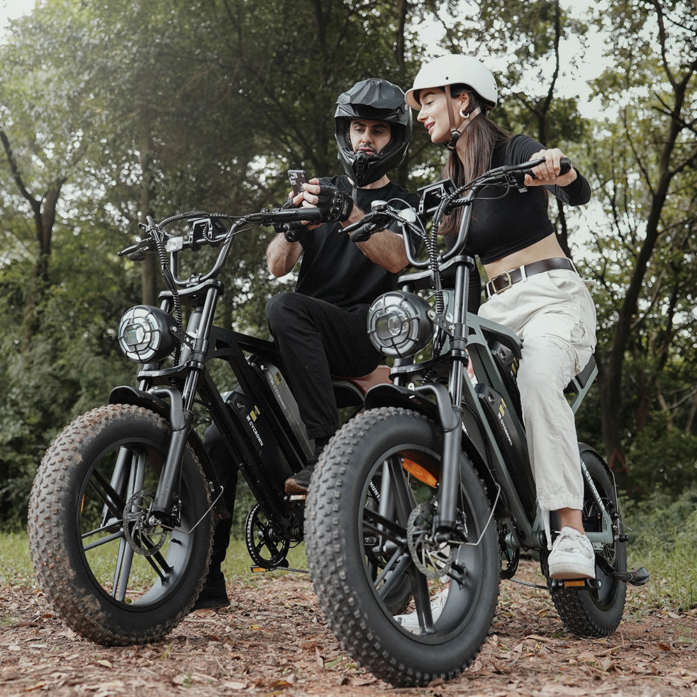 Two riders posing with black and mint green CycHunter bikes in the woods