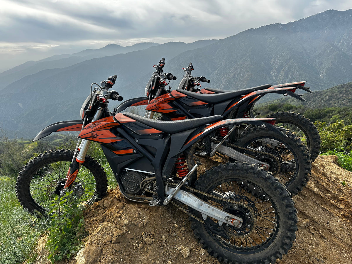Trailblaze Motors Omega electric dirt bike lineup at a mountain overlook