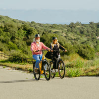 Two riders using VTUVIA Zeal LT7 e-bikes on a paved coastal route