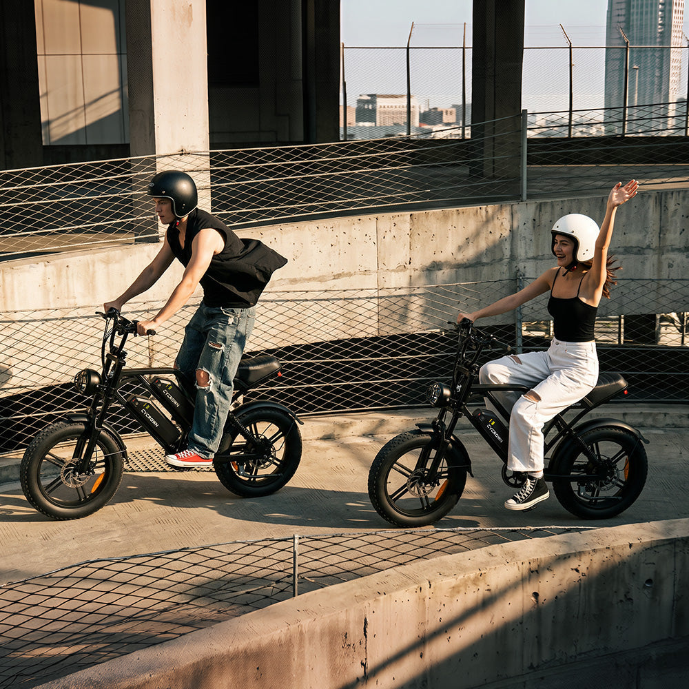 Two helmeted riders cruising on CycHunter 2.0 bikes through the city