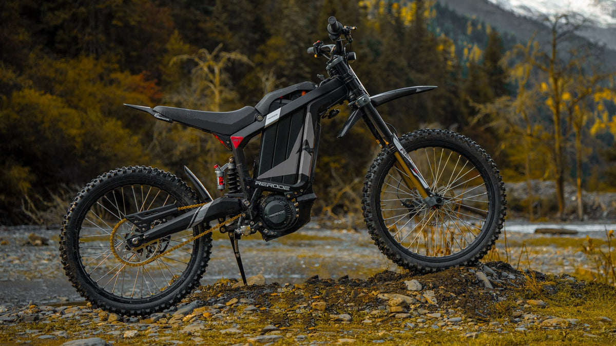 RERODE R1-19 electric dirt bike parked beside a rocky mountain trail